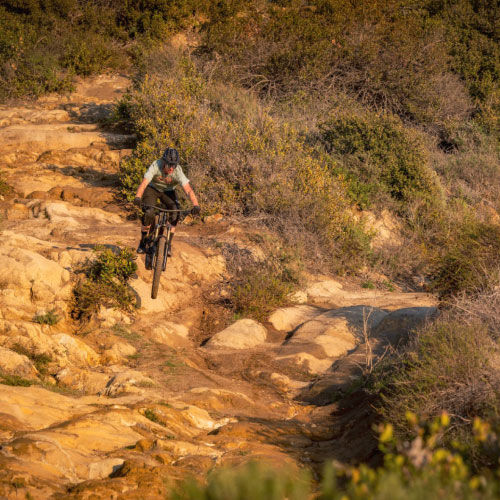 A lone mountain biker riding through a rock garden.